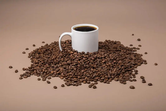 A cup of freshly brewed premium coffee surrounded by roasted coffee beans.