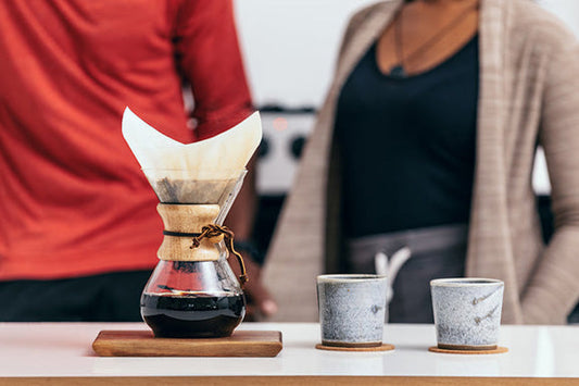 Chemex with two coffee cups and two persons talking