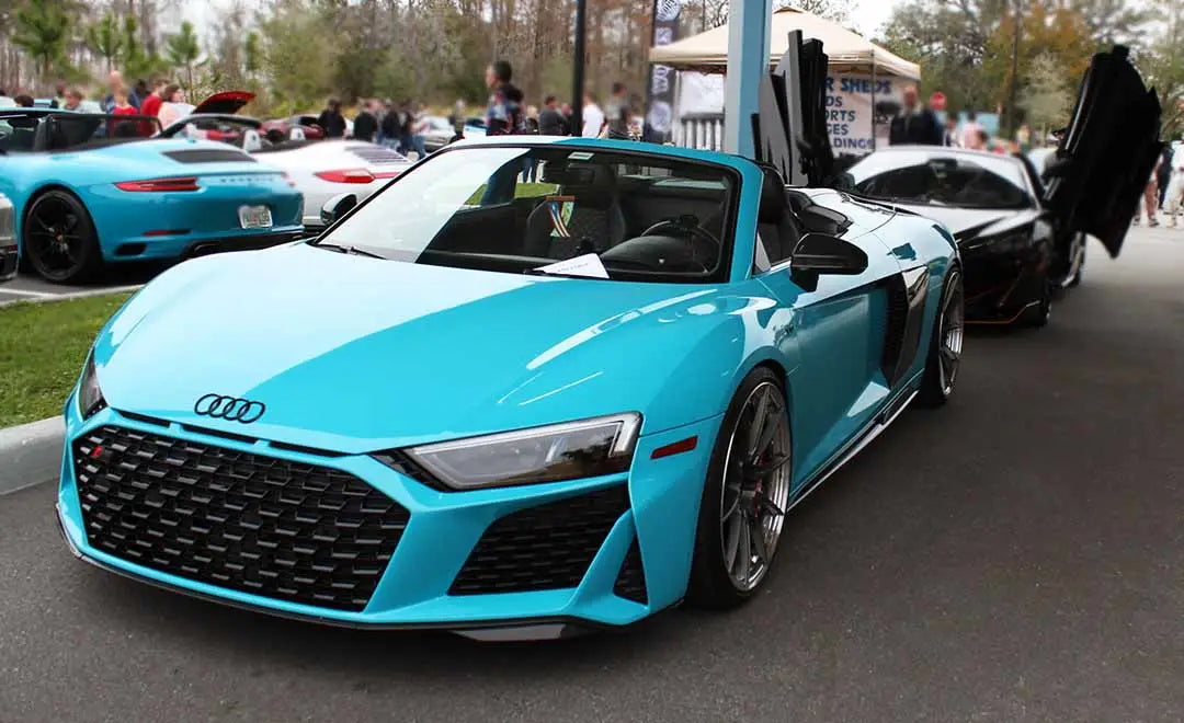 Blue Audi R8 Convertible on display at Cars and Coffee event, surrounded by car enthusiasts.