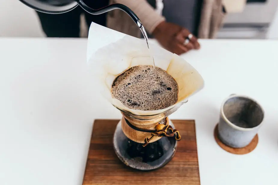 A mesmerizing top-down view of a pour-over coffee brewing method. Freshly ground coffee is being carefully poured over a ceramic dripper, with hot water gracefully flowing through the coffee grounds, creating a rich and aromatic brew.